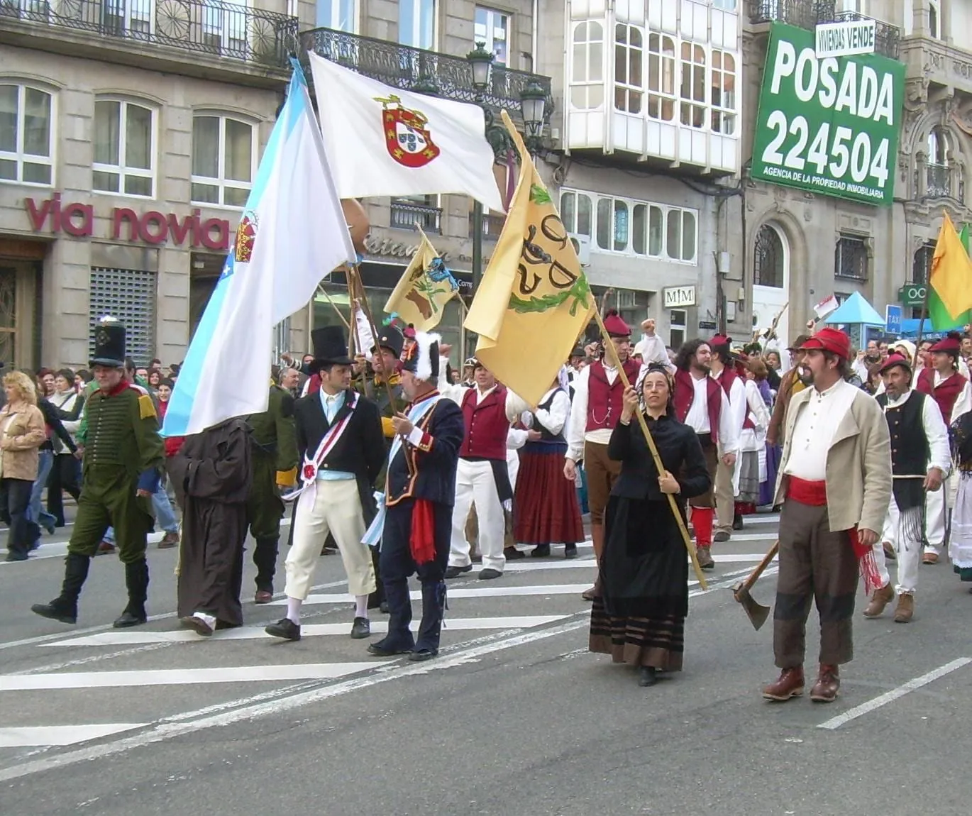Desfile de vecinos vestidos de época con banderas y un hacha por una calle de Vigo durante la Reconquista
