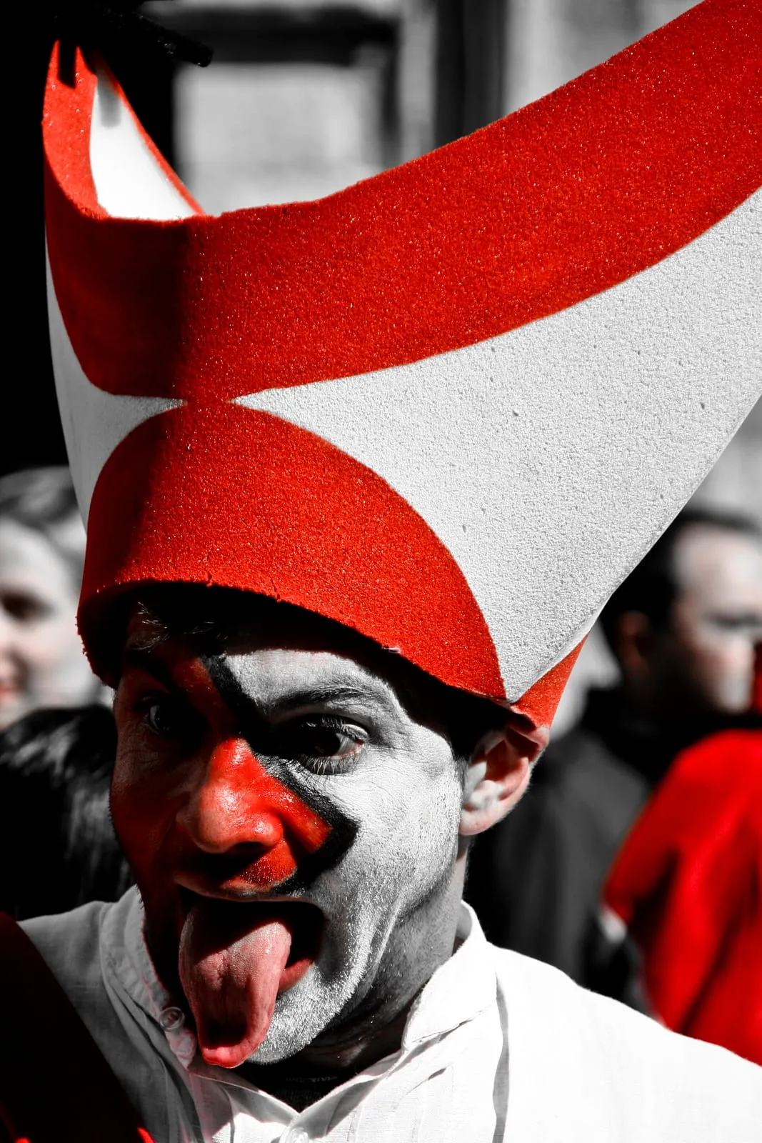 Retrato de un participante con la cara pintada y un gran gorro rojo y blanco durante la fiesta