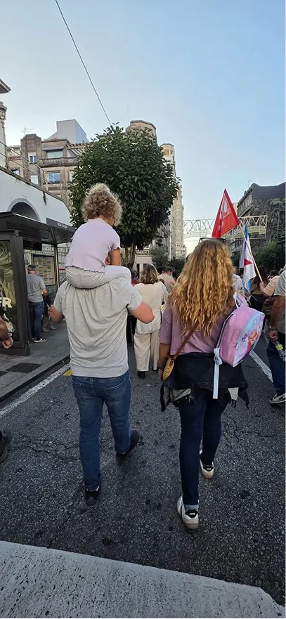 Un hombre con un niño a hombros camina entre los asistentes a la manifestación por la vivienda en Vigo