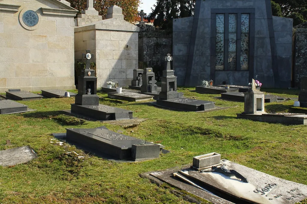 Panteones de piedra y tumbas de granito oscuro sobre césped en el cementerio de Pereiró