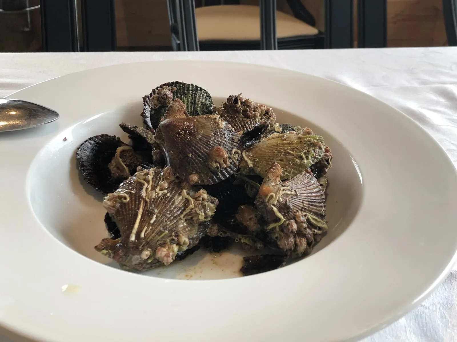 Plato de zamburiñas negras cocinadas, todavía con su concha