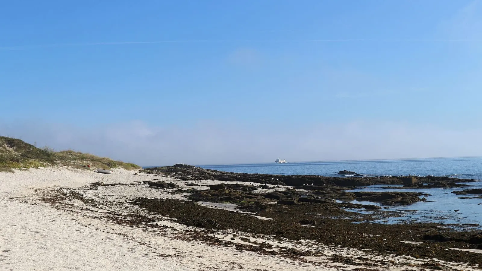 Arena blanca y rocas en la orilla de la playa de Canexol, en la isla de Ons