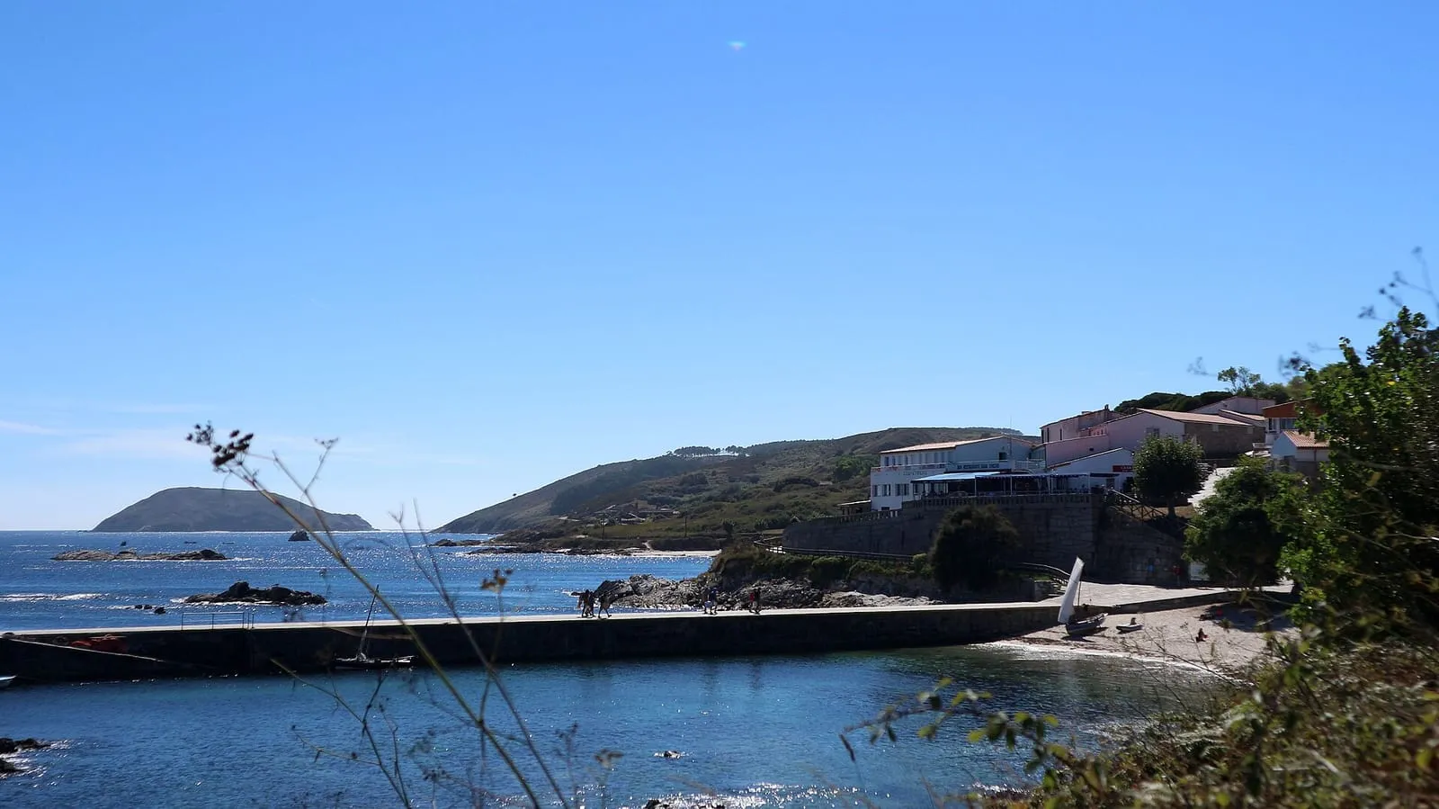 Muelle de O Curro en la isla de Ons, con las casas del núcleo y la ría de Pontevedra al fondo