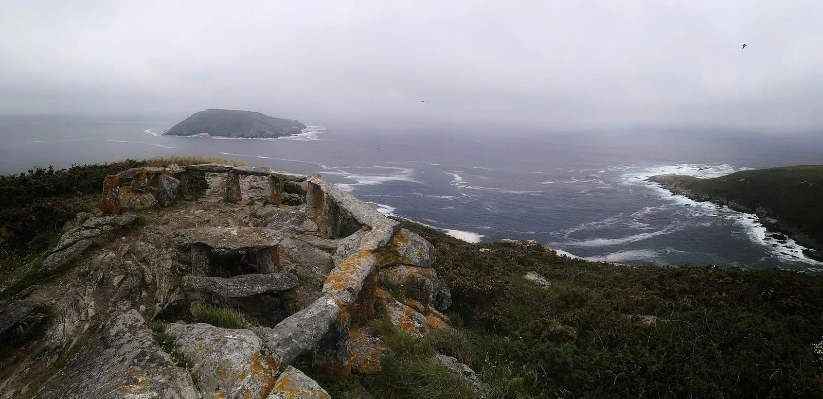 Mirador de piedra de Fedorentos sobre los acantilados del sur de Ons, con la isla de Onza en el mar