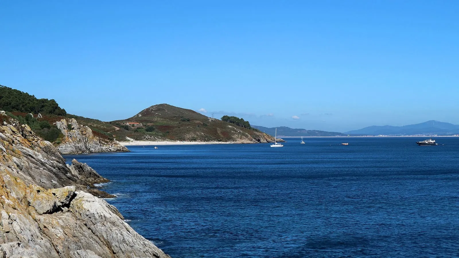 Cala de aguas azules y costa rocosa vista desde Punta do Castelo, en la isla de Ons