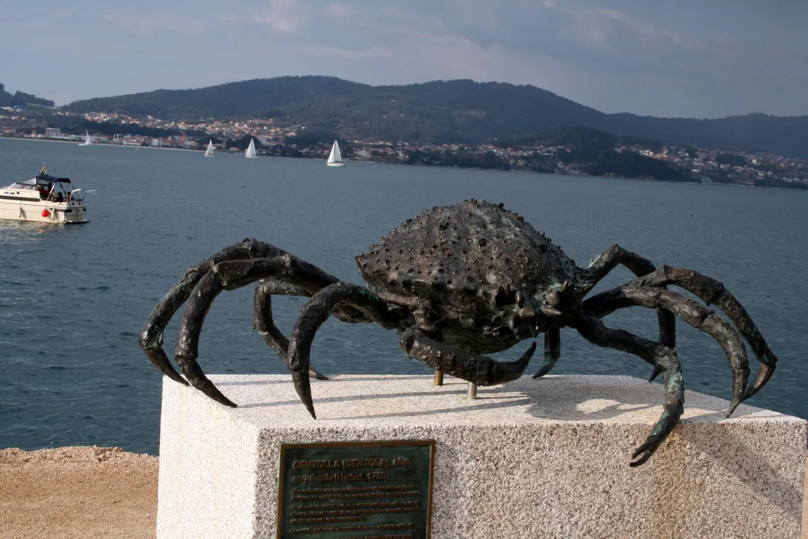 Escultura de bronce de un centollo sobre una peana de granito junto a la ría de Vigo