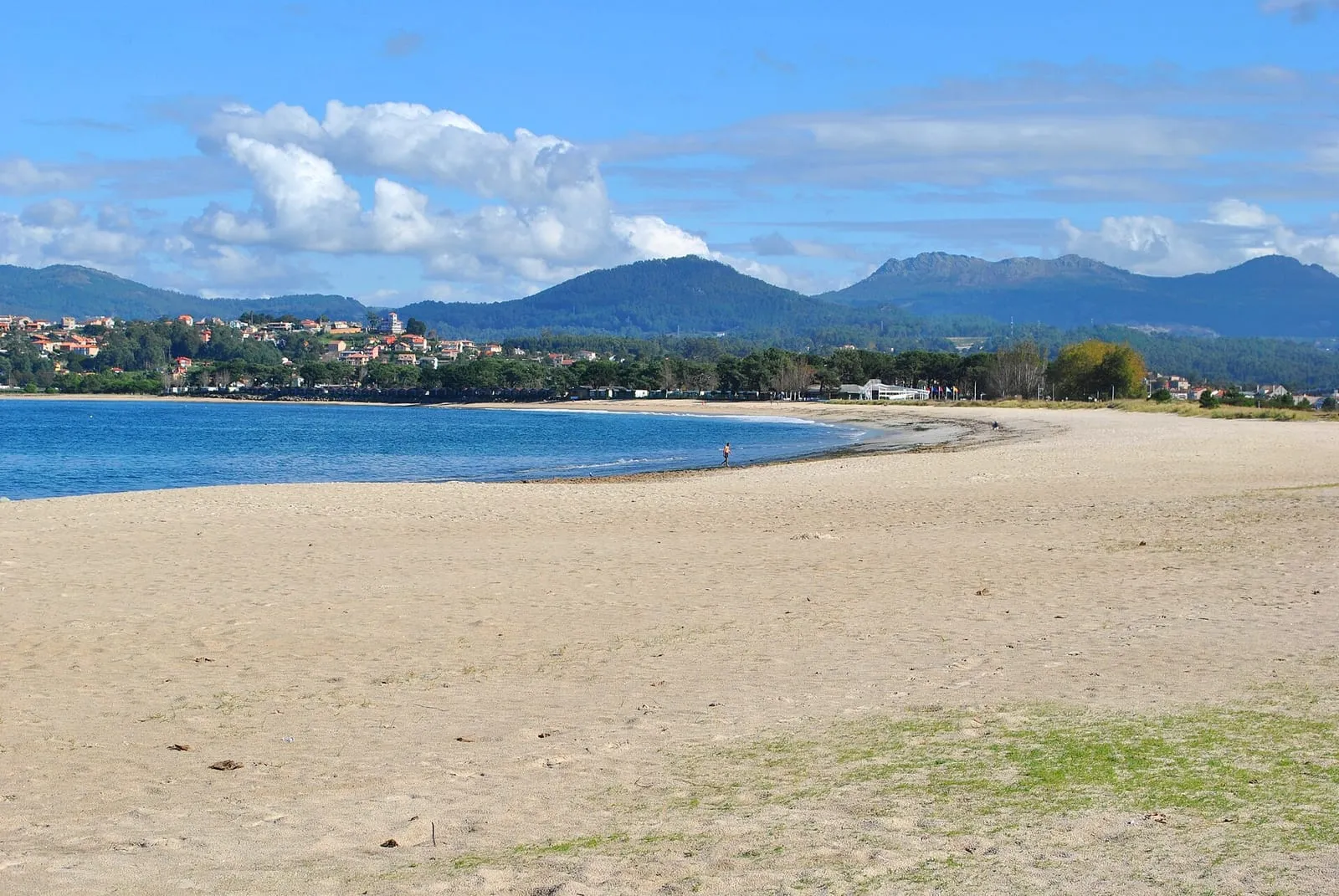 Playa da Ladeira en Baiona vista desde la arena, con el pueblo y los montes al fondo