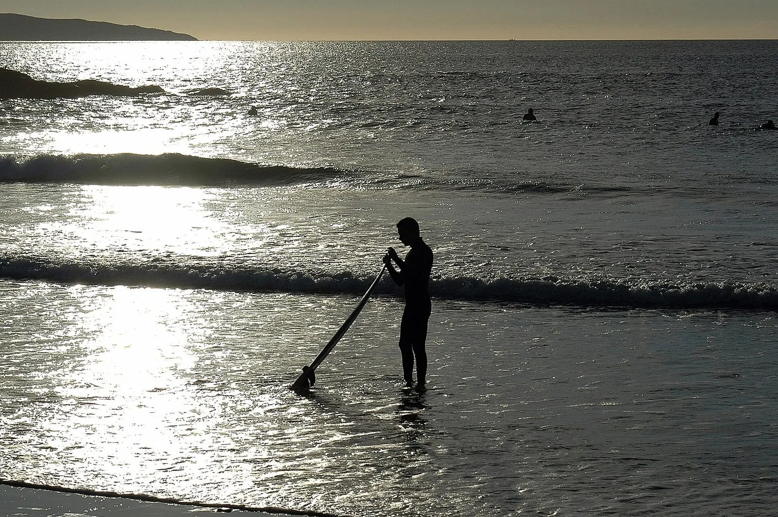 Persona haciendo paddle surf al atardecer en la playa de A Lanzada