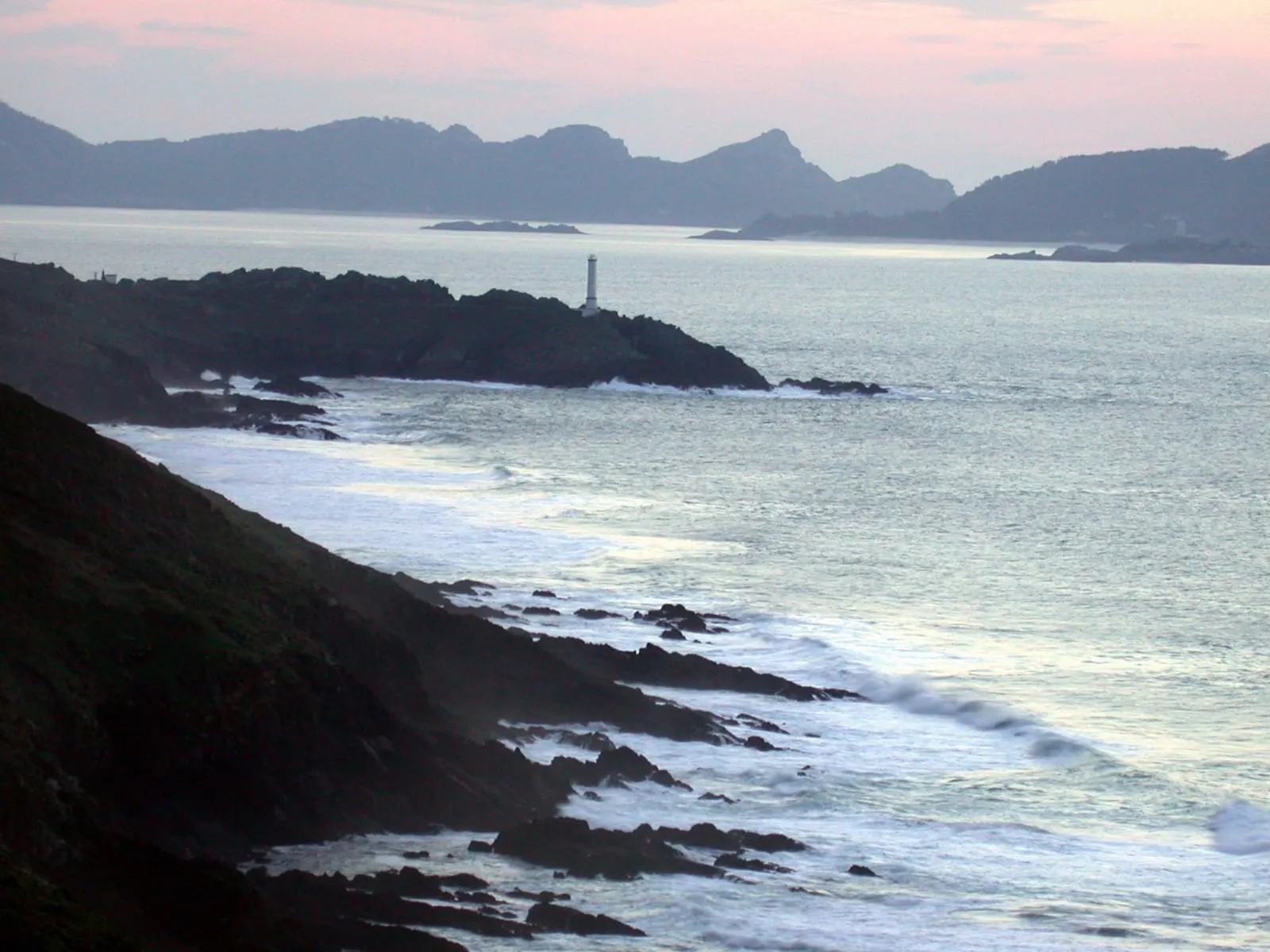 Faro de Punta Robaleira al atardecer con la silueta de las Islas Cíes al fondo