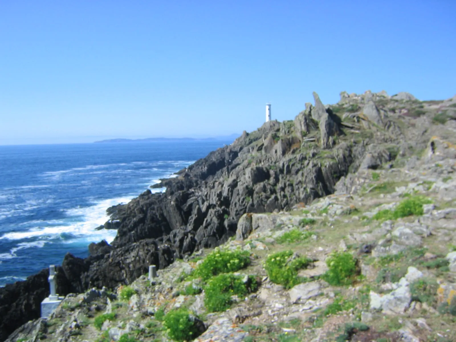Sendero sobre los acantilados de Cabo Home con un faro al fondo